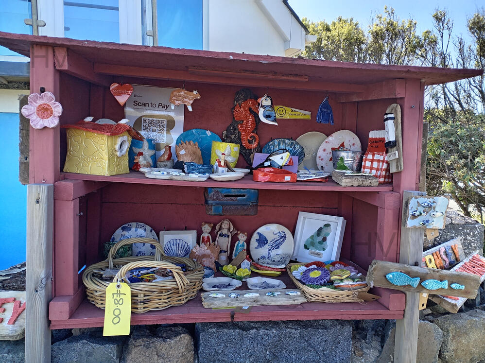 road side plants for sale. Drop money in letter box. wooden shed surrounded by roses