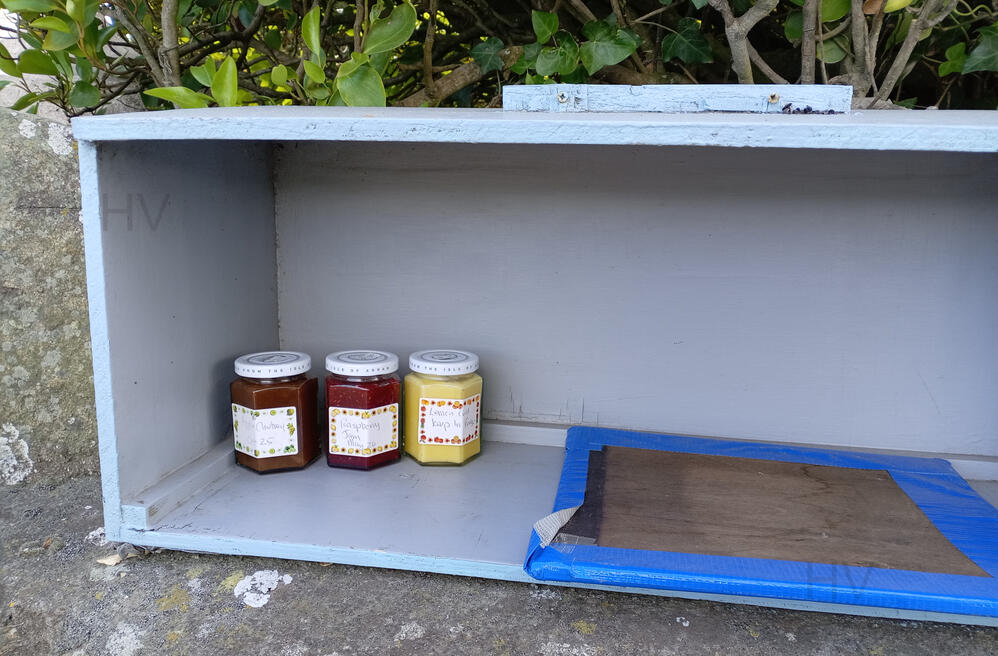 honesty stall selling jams and chutneys wooden shed surrounded by roses
